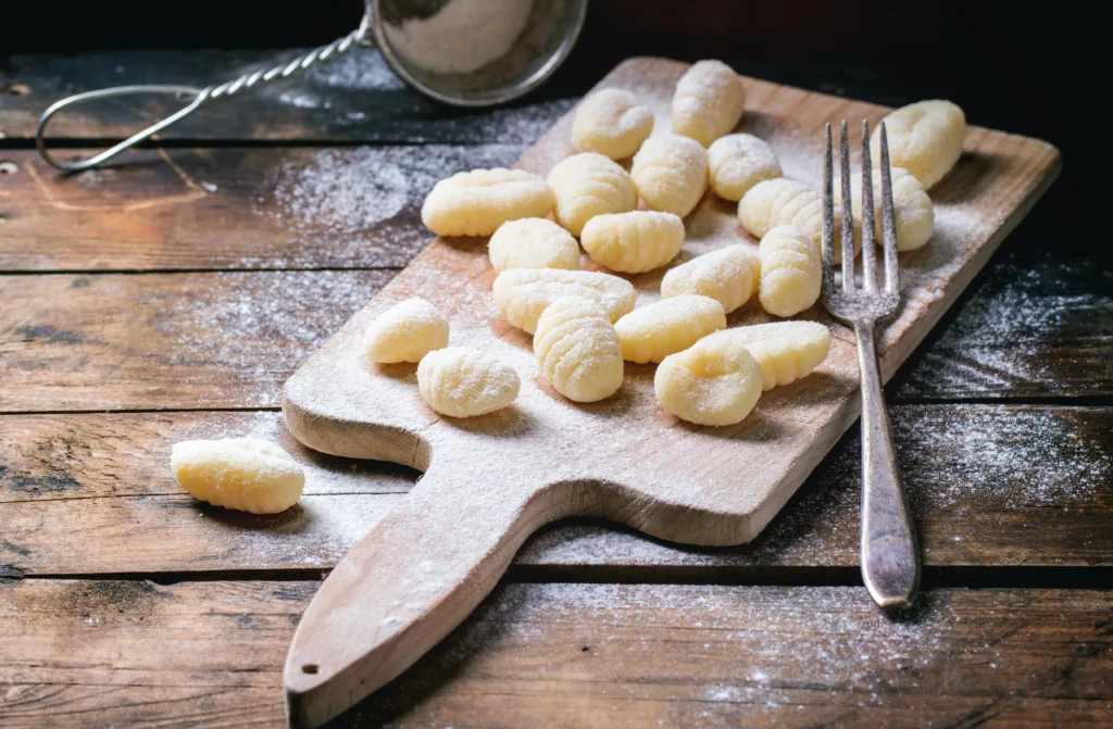 Gnocchi maison servis faits à l'aide d'une fourchette sur une planche en bois avec de la farine