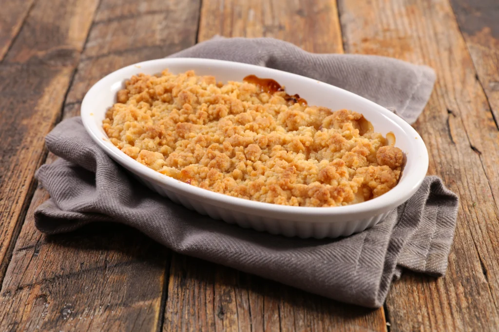 Photo d’un crumble pomme kiwi qui sort du four, doré avec une texture croustillante, idéal pour un dessert gourmand et original