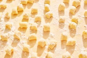 Gnocchi maison en cours de découpe sur un plan de travail fariné