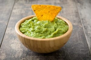 Bol de guacamole maison accompagné de chips de maïs, parfait pour un apéritif ou un repas convivia