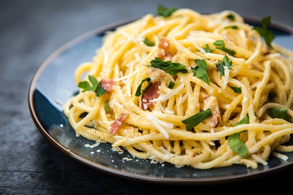 Assiette de pâtes à la carbonara, avec guanciale croustillant, pecorino romano et jaune d'œuf, servie dans une belle assiette