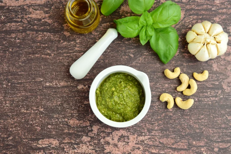 Bol de pesto avocat crémeux avec basilic ail et noix de cajou et huile d'olive sur une table en bois