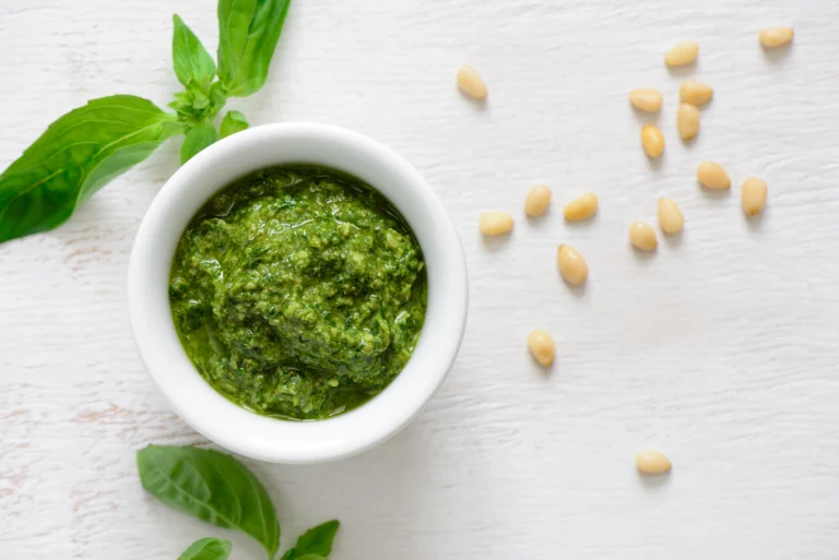 Pot de pesto fait maison avec des feuilles de basilic frais, des pignons de pin et du parmesan râpé