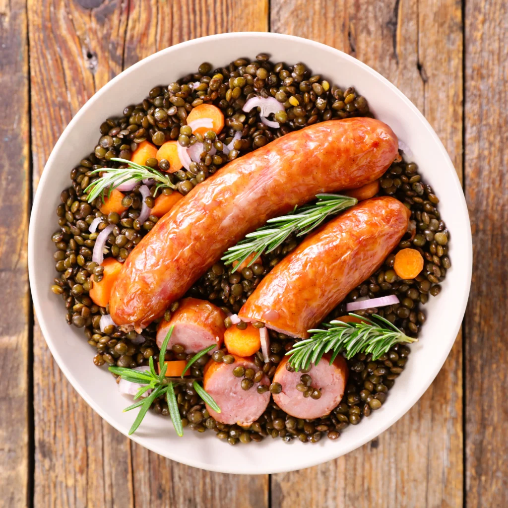 Plat de saucisses de toulouse aux lentilles mijoté, préparé selon une recette de grand-mère, avec du romarin de la carotte et de l'échalotte