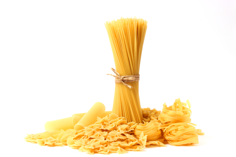 Assortiment de pâtes sèches crues : spaghetti, farfalle, tagliatelles et rigatoni disposés sur fond blanc
