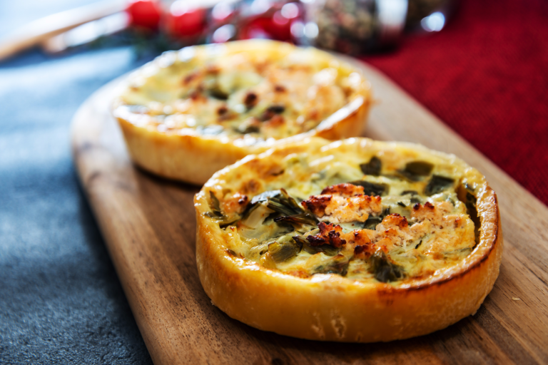 Tartelettes salées aux légumes et fromage dorées au four, servies sur planche en bois, parfaites en entrée chaude