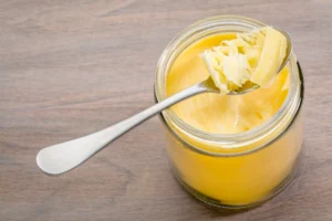 Gros plan sur du beurre clarifié solide dans un pot en verre, avec une cuillère