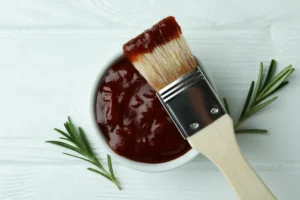 Bol de sauce barbecue maison avec pinceau culinaire et brins de romarin
