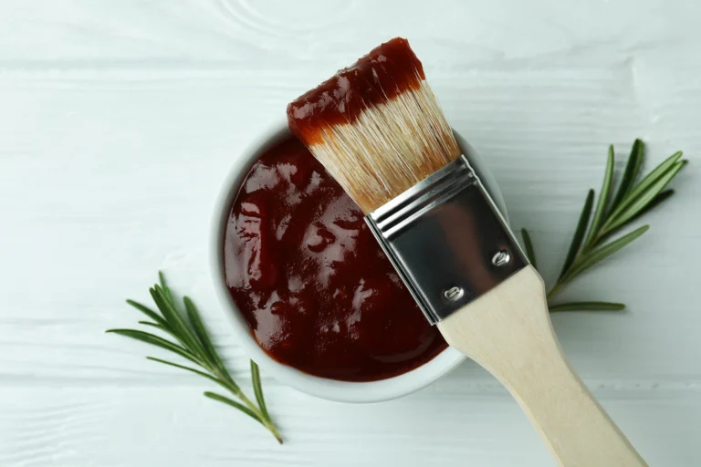 Bol de sauce barbecue maison avec pinceau culinaire et brins de romarin