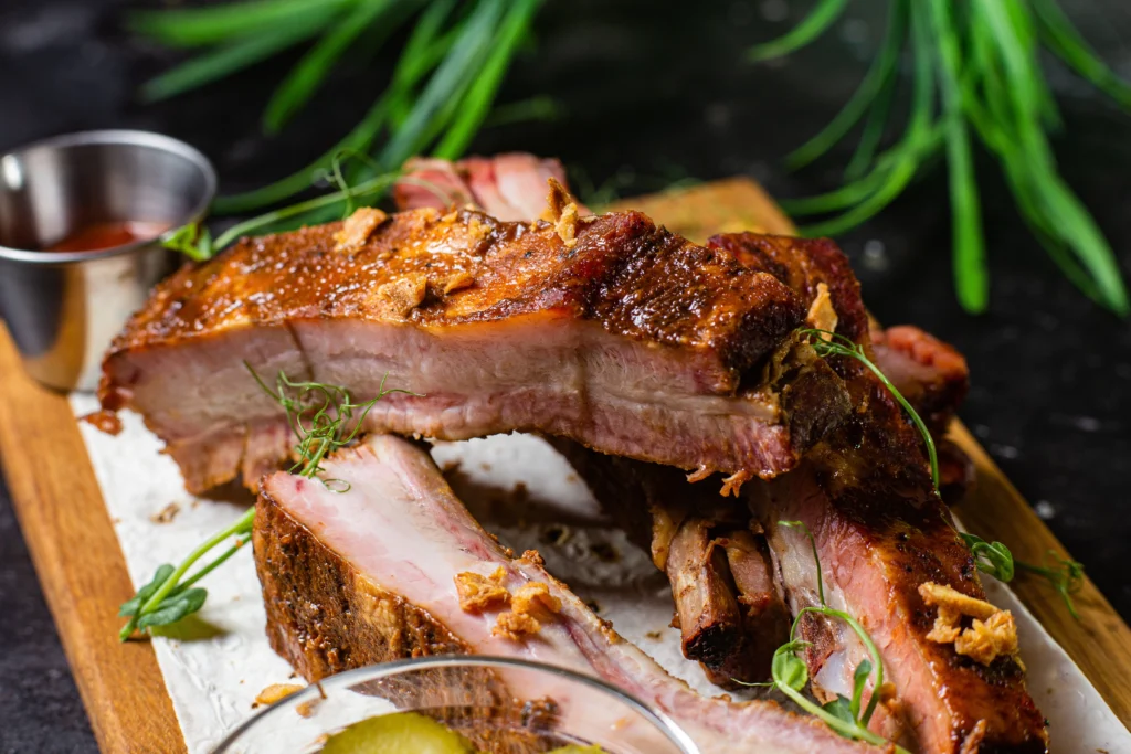 Travers de porc fondants cuits au four, dorés et caramélisés, servis sur planche en bois