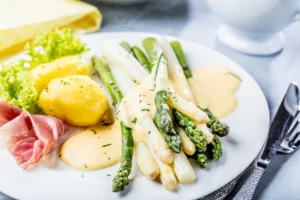 Assiette d’asperges vertes et blanches nappées de sauce mousseline avec pommes de terre et jambon cru
