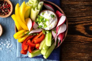 Bol de sauce au yaourt garnie d'oignon vert, entourée de crudités fraîches