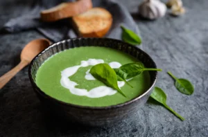 Bol de soupe d’épinards à la crème avec croûtons et crème fraîche