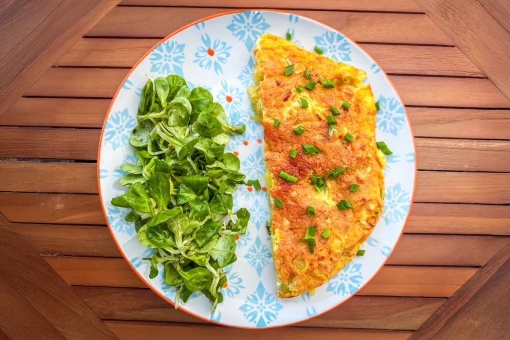 Tortilla espagnole maison aux pommes de terre servie avec une salade de mâche