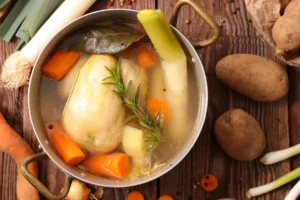 Recette de poule au pot traditionnelle servie avec carottes, navets, poireaux poireaux et pommes de terre