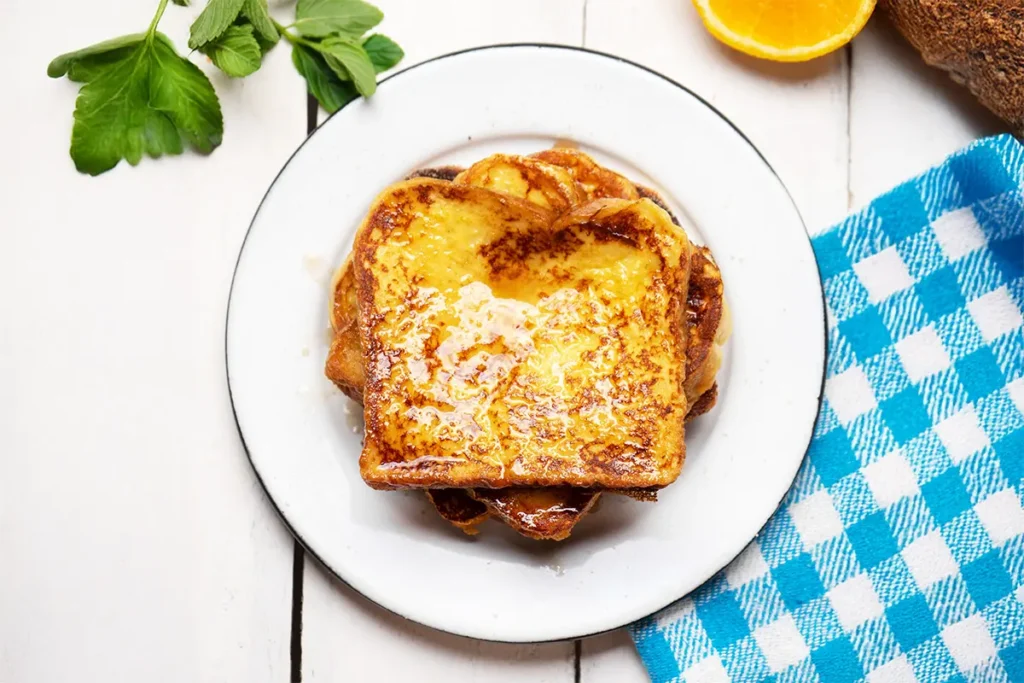 Pain perdu maison doré et moelleux, servi sur assiette avec serviette rustique – recette facile de grand-mère