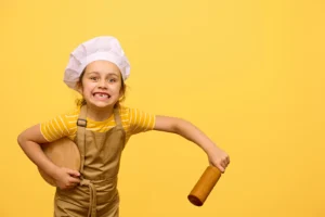 Petite fille en toque et tablier prête à cuisiner, idée ludique pour illustrer des recettes à faire avec les enfants