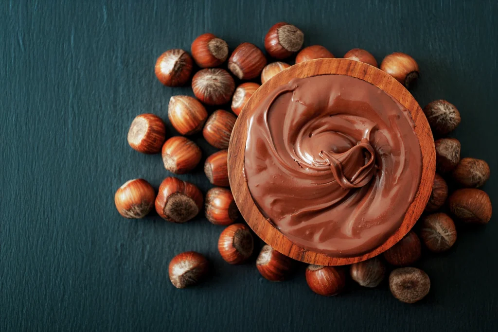 Pâte à tartiner maison avec 3 ingrédients : chocolat, huile et noisettes dans un bol en bois