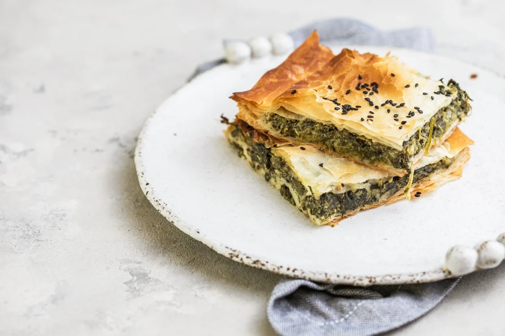 Spanakopita maison dorée, garnie d’épinards et de feta, servie sur assiette