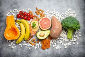 Aliments riches en potassium : avocat, banane, saumon, légumineuses, brocoli et patate douce sur fond neutre