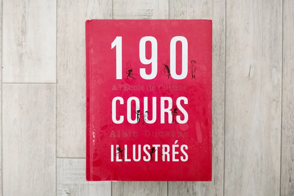Livre 190 cours illustrés d'Alain Ducasse posé à plat sur un sol en bois clair