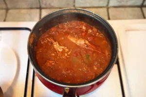 Gambas à la catalane qui mijotent dans une cocotte, en sauce tomate aux poivrons et aromates