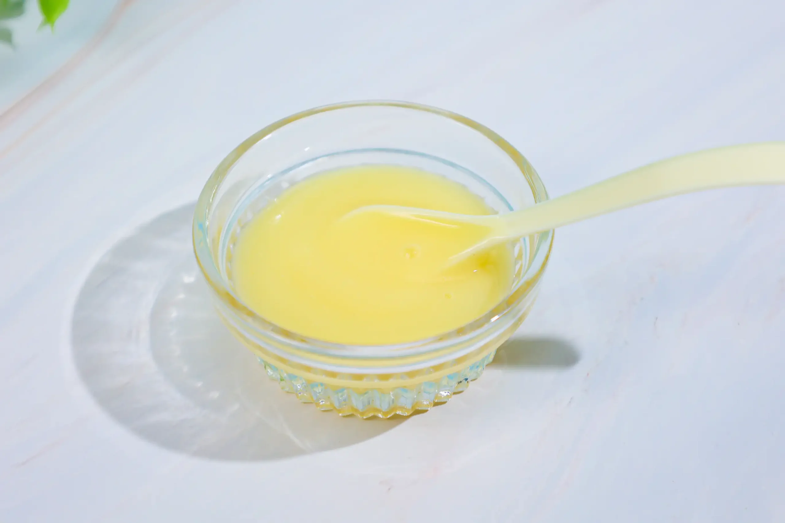 Gelée royale fraîche jaune pâle servie dans un bol en verre avec cuillère