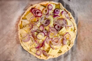 Tarte aux courgettes, burrata, crème de pesto et oignons rouges avant cuisson, prête à enfourner