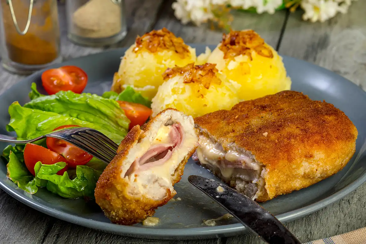 Cordon bleu maison pané avec jambon et fromage, servi avec salade et pommes de terre