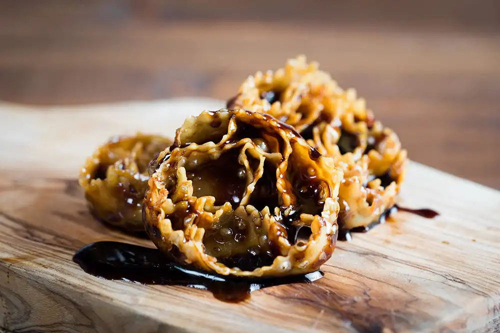 Cartellate italiennes, rosaces de pâte frite nappées de vincotto, dessert traditionnel des Pouilles servi pendant les fêtes de Noël.