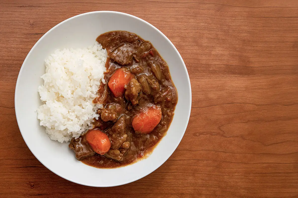 Recette de curry japonais maison avec riz blanc, plat servi dans une assiette blanche sur fond bois