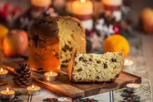 Panettone italien traditionnel de Noël, brioche moelleuse aux fruits confits et raisins secs entourée de bougies et décorations de fêtes.