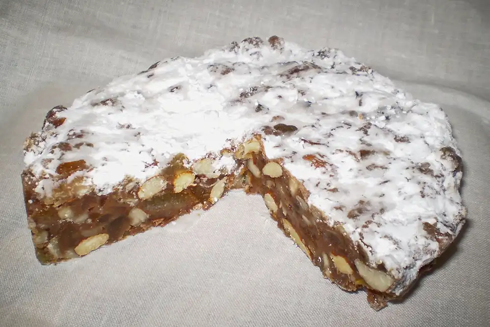 Panforte de Sienne, dessert de Noël italien traditionnel à base de miel, amandes et fruits confits, recouvert de sucre glace.