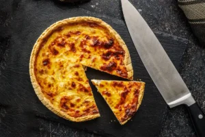 Vraie recette de quiche lorraine traditionnelle, dorée au four, servie sur ardoise