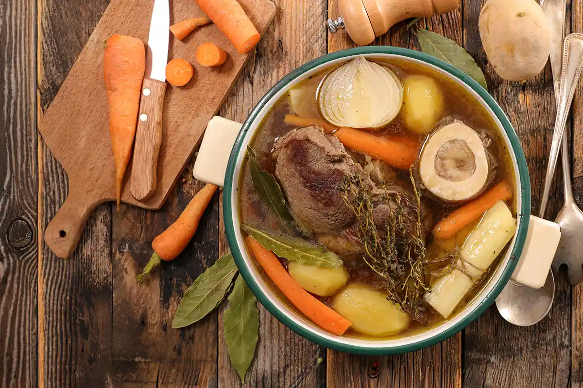Photo d’un pot-au-feu traditionnel maison avec viande de bœuf, os à moelle, carottes, poireaux et pommes de terre dans un bouillon clair