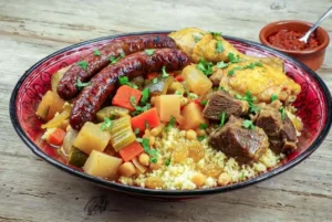Recette du couscous royal traditionnel aux trois viandes avec semoule, légumes, pois chiches et harissa