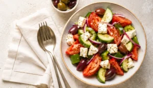 Recette de salade grecque maison : tomates, concombres, oignons rouges, cubes de feta et olives Kalamata.