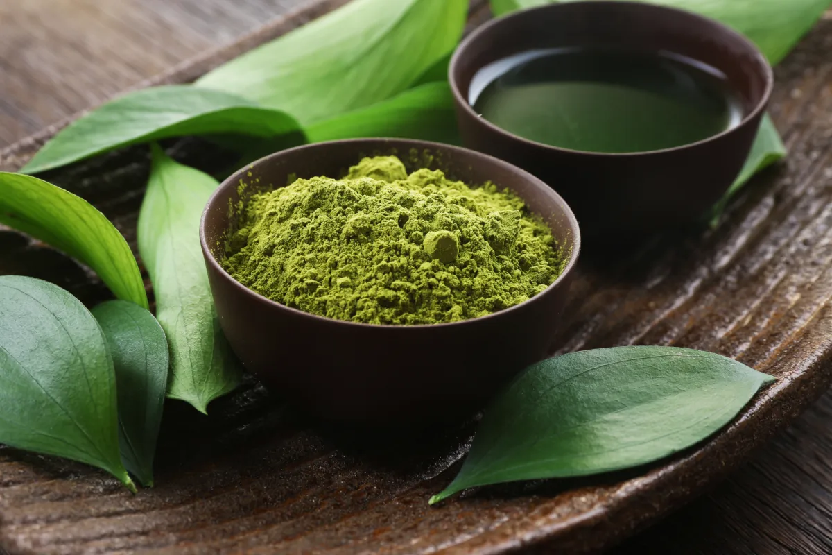 Poudre de thé matcha vert dans un bol avec une tasse de thé, pour illustrer les bienfaits du matcha
