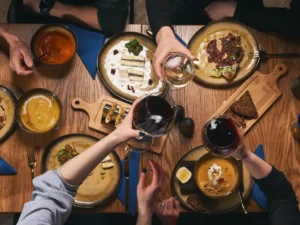 Table de restaurant vue de dessus avec assiettes Ă partager et verres lors dâun dĂźner tardif entre amis.