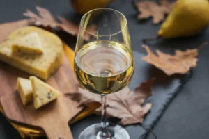 Verre de vin blanc servi avec plusieurs fromages sur une planche, pour illustrer les accords mets vins.