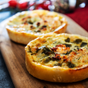 Tartelettes salées aux légumes et fromage dorées au four, servies sur planche en bois, parfaites en entrée chaude